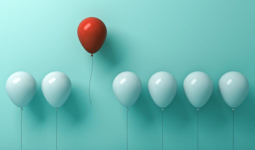 One red balloon flying away from white balloons on light green pastel colour wall.